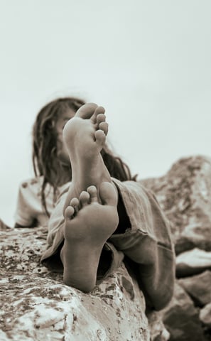 a little girl is sitting on a rock