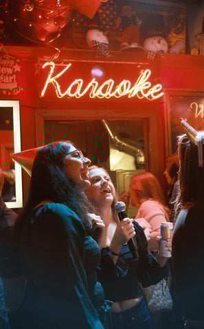 a woman singing into a microphone while standing in front of a karaoker
