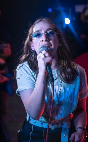 a woman in sunglasses and sunglasses is holding a microphone