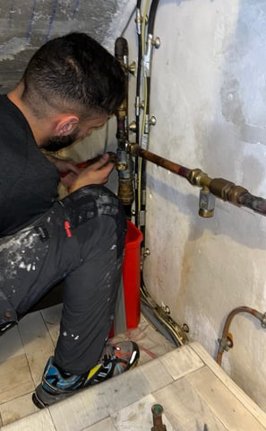 a man in a black shirt is fixing a pipe