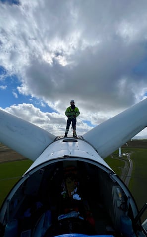 a man standing on top of a turbine