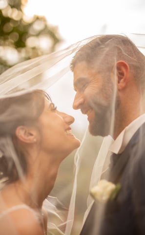 a bride and groom are standing in front of a veil