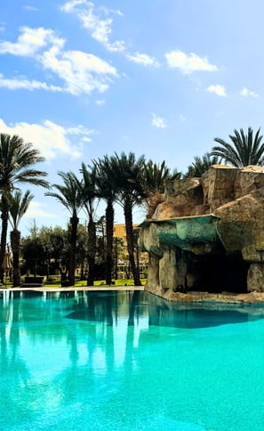 "Piscine extérieure de l’hôtel Russelior entourée de palmiers, cadre paisible pour les vacances bien-être The Best You"
