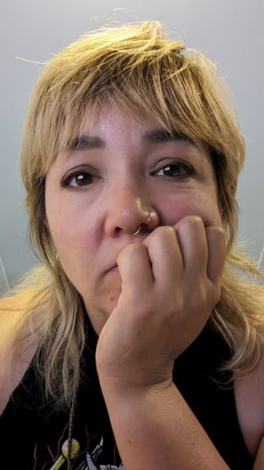 Lindsay, a mixed-race woman with blonde hair, looks at the camera with her chin resting on one hand.