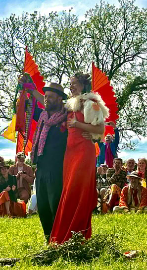 large outdoor spring handfasting ceremony of royal orange and navy blues, yellows and golds.