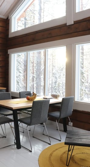 dining room table in log house with large panoramic windows and views of snowy forrest