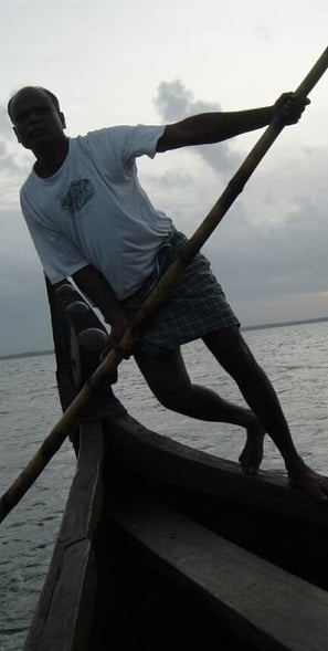 Man punting traditional wooden boat in Kerala backwaters