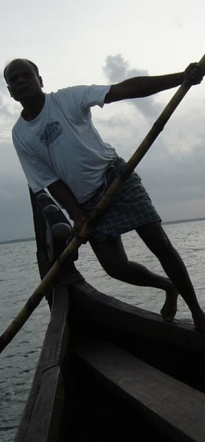 Man punting traditional wooden boat in Kerala backwaters