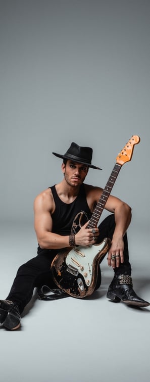 a vocalist in a hat with a guitar