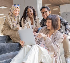 a group of people sitting on steps with a laptop