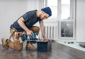 a man in a blue hat and a blue hat is holding a circular sawdust