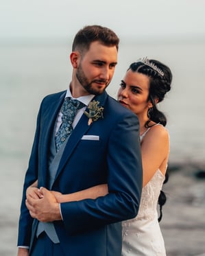 una novia y un novio en una playa abrazándose en el día de su boda