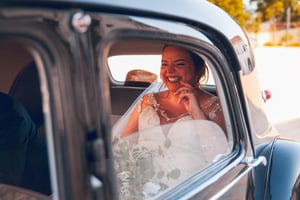 Bride laughing and enjoying her ride in a classic car