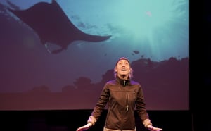 Julia Duchaussoy sur scène avec une raie Manta en arrière plan