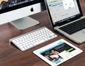 Teclado y portátil sobre escritorio con sitio web abierto, mostrando diseño web profesional.
