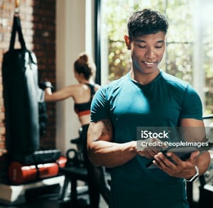 a man in a gym with a tablet and a woman in a gym