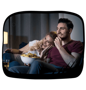 a man and woman sitting on a couch watching tv