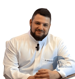 dr. Adeilson sentado com o jaleco em uma consulta