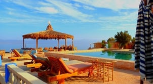 a beach camp pool with lounge chairs and umbrellas