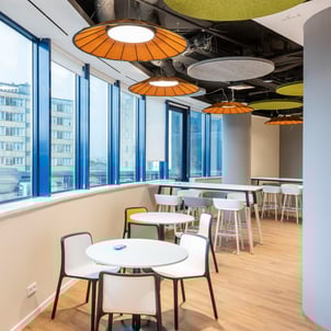 Sala de estar con mesas redondas, sillas y paneles acusticos (Resting area with round tables, chairs and acoustic panels)
