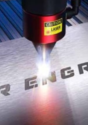 Una máquina de grabado láser en el proceso de grabado de una placa de metal.