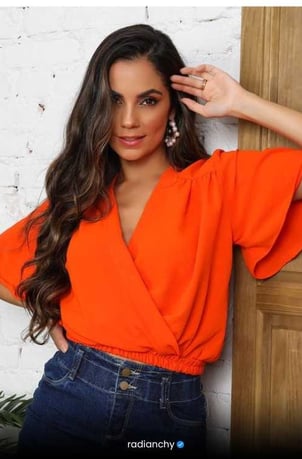 a woman in a bright orange top and jeans