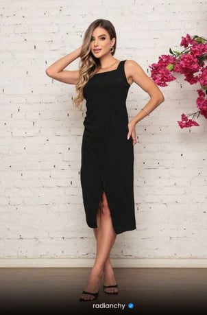 a woman in a black dress standing in front of a white brick wall