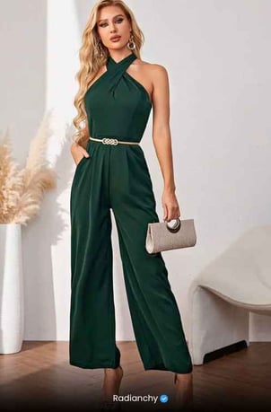 a woman wearing a green jumpsuit with a clutch bag