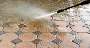 a person using a hose to clean a brick floor
