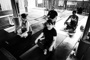 Students sit in Easy Pose at the start of a yoga class at The Bamboo Cottage Langkawi