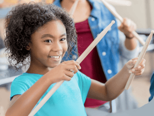 child smiling playing drums