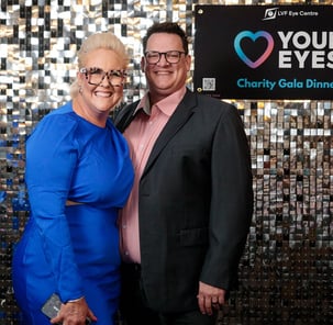 2 guests smiling in front of the SweetAz Co. silver shimmer wall hired for the Layton Vision Foundation Charity Gala Herston