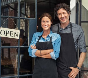 A husband and wife standing in front of their business that they own together