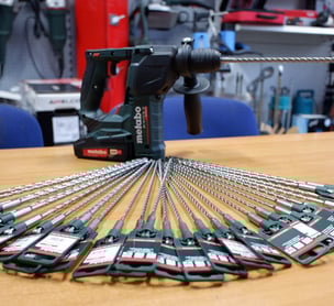 foto di un trapano marca metabo sopra un tavolo e delle punte del trapano