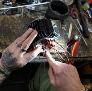 Riparazione di un motore elettrico, nella foto sono presenti due mani che riparano un motore