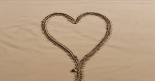 heart drawn on sand during daytime