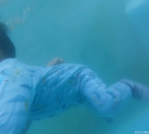 a baby in a blue suit is swimming in the water