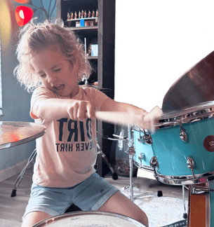 little girl playing blue drums