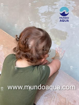 a child's hand is touching the water