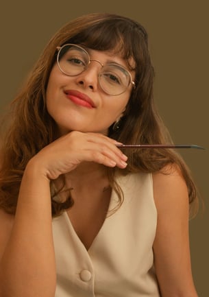 Foto de perfil da Leile segurando um pincel e sorrindo