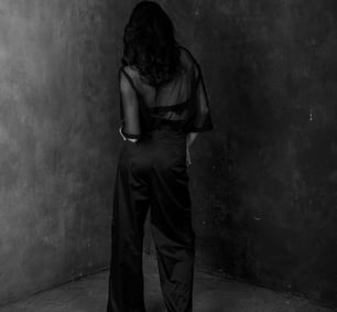 The back of a stylish brunette woman in all black wearing and in black heels