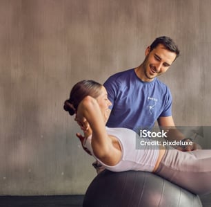 a man and woman doing a back stretch while sitting on a ball