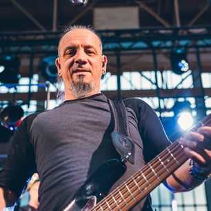 Un guitariste sur scène souriant face à la caméré