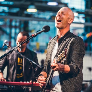 Un chanteur et guitariste de rock face au micro et les yeux fermés