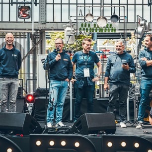 5 hommes sur une scène avec un sweat shirt bleu foncé