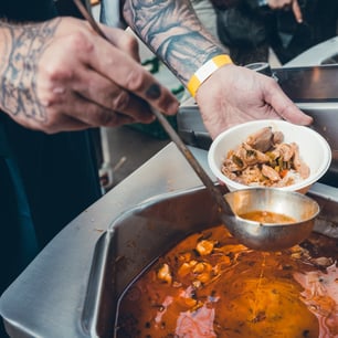 Les mains d'un cuisinier servant du sauté de volaille dans une assiette