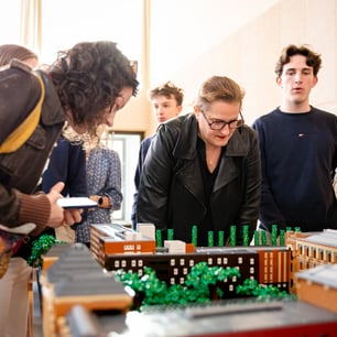 Un ensemble de personnes réunies autour d'une maquette de batiments en Lego