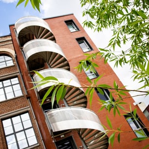 Un escalier en inox extérieur avec une façade en brique rouge