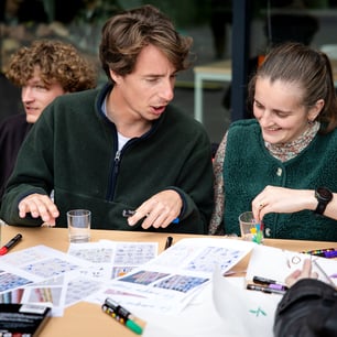 Un ensemble de personnes assises autour d'une table et travaillant sur des exercices écrits