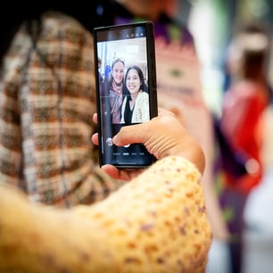 Un gros plan sur un smarthphone prenant un selfie de sa propriétaire et d'une autre personne